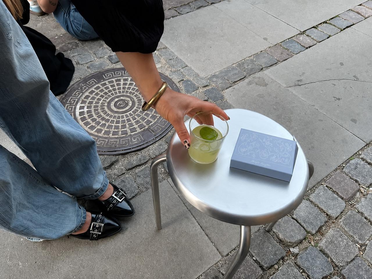 Thought Daughter cards placed beside a drink on a metal stool